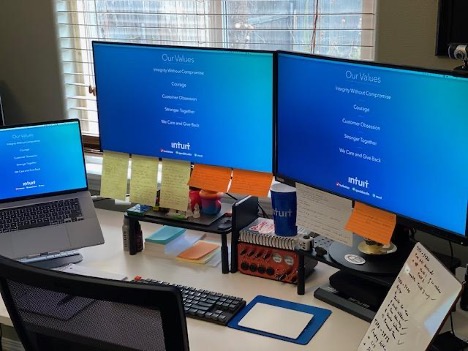 Gil's work station with sticky notes and light colored themes on his computer monitors.